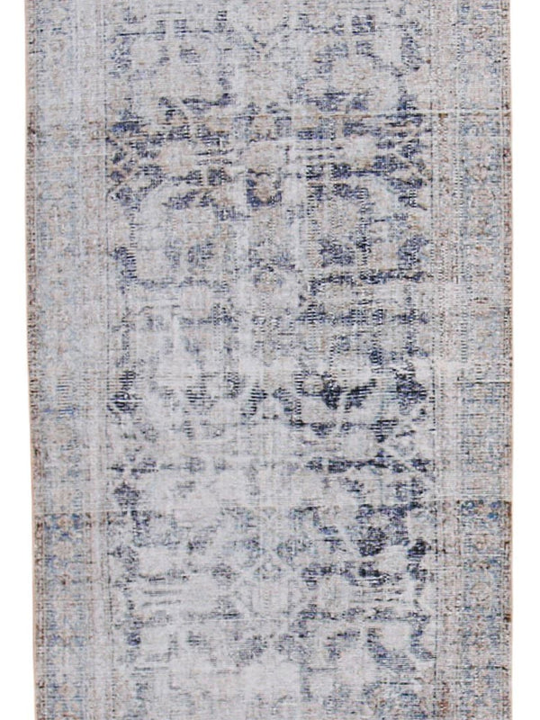 A rectangular distressed area rug with an abstract, faded medallion pattern in muted shades of gray, beige, and light blue.