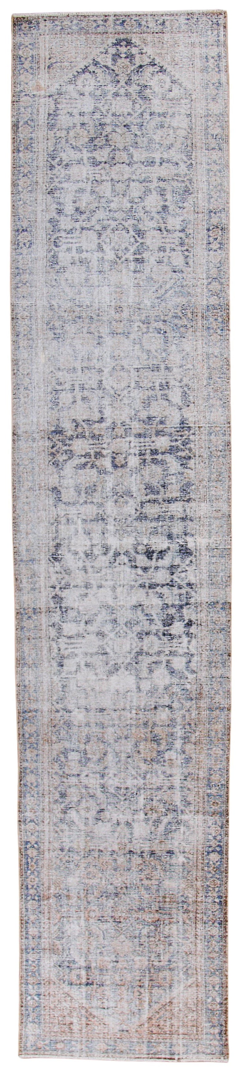 A rectangular distressed area rug with an abstract, faded medallion pattern in muted shades of gray, beige, and light blue.